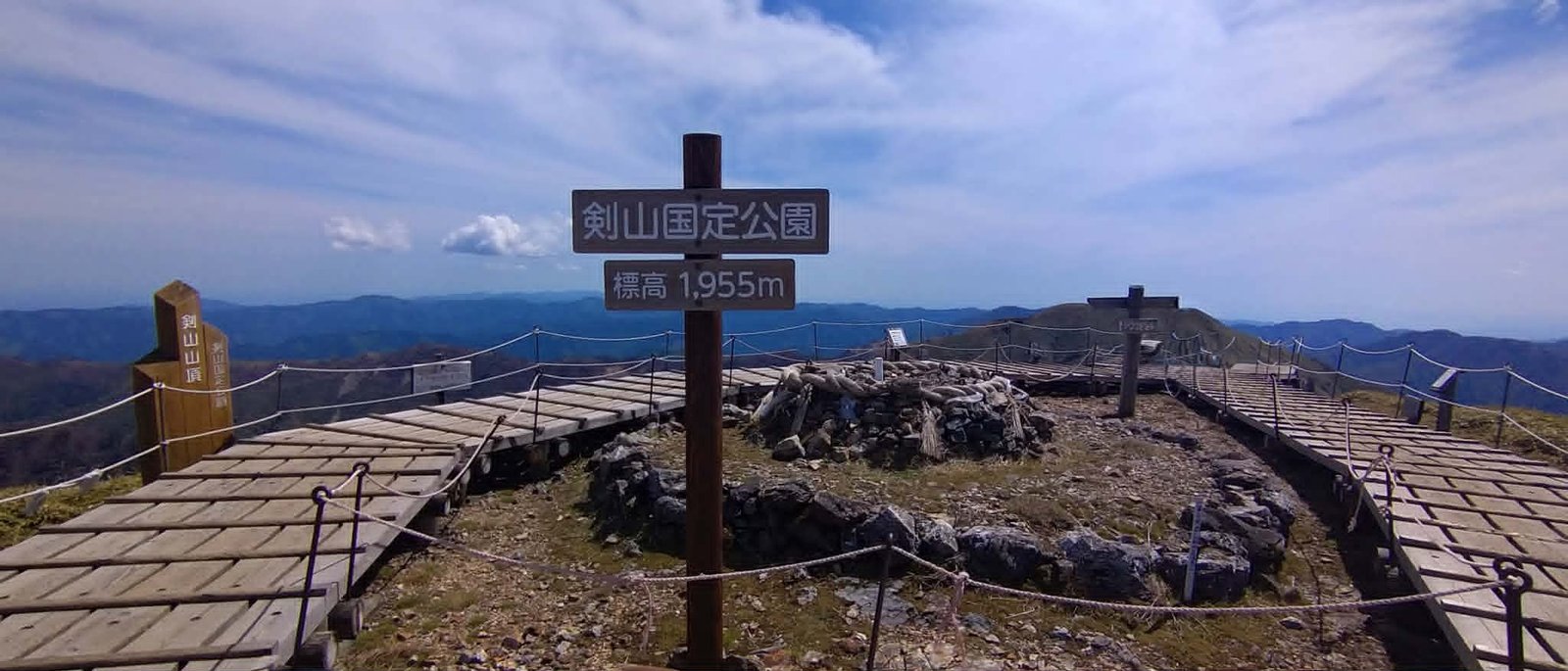 The summit of Ken-zan (1,955 m), Tokushima — the park signpost, wooden boardwalk, and the sacred rock wrapped in shimenawa rope