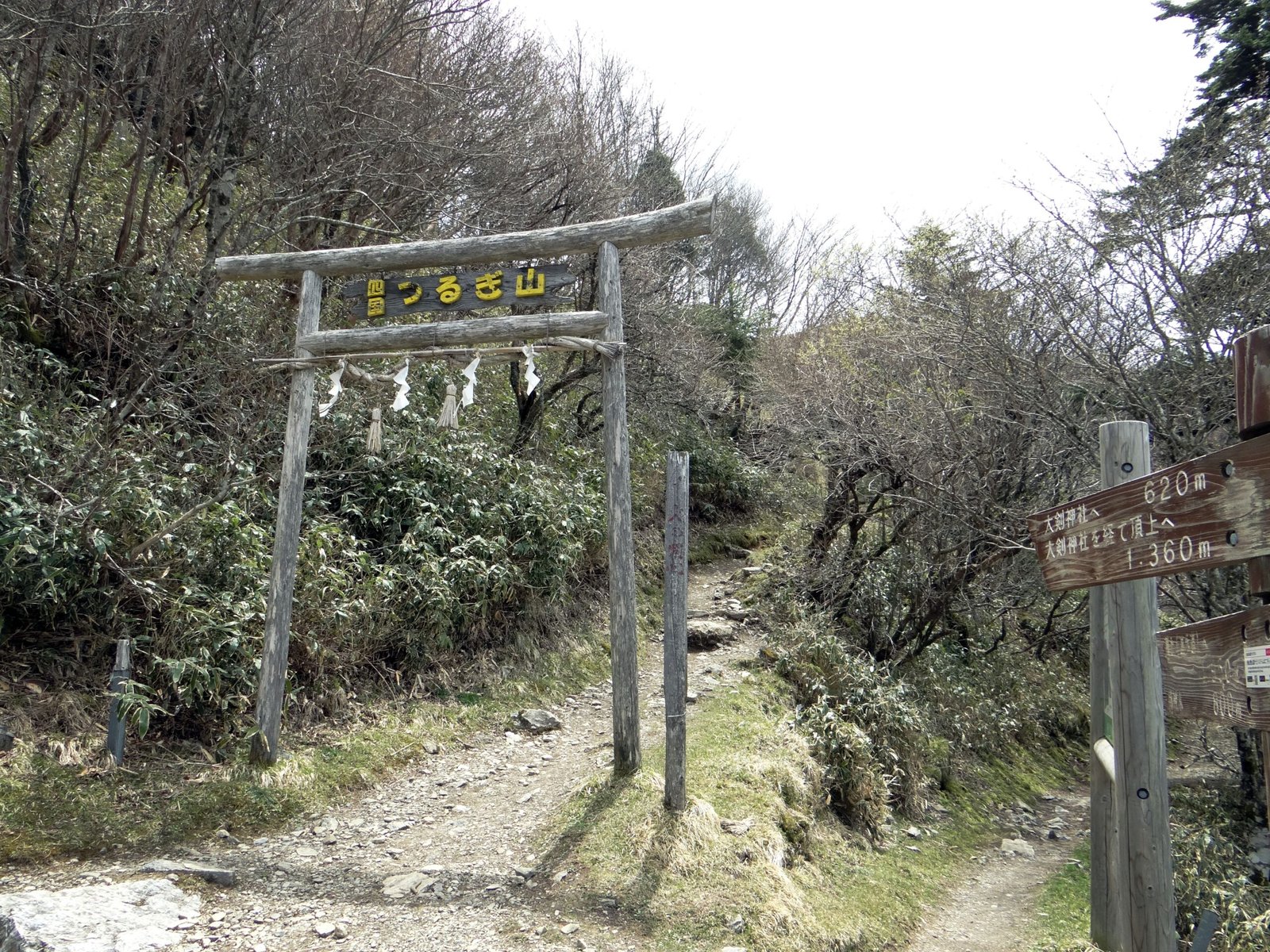 Wooden torii marking the entrance to a summit trail on Ken-zan (Mount Tsurugi), Tokushima, with a signpost pointing toward Otsurugi Shrine and the peak