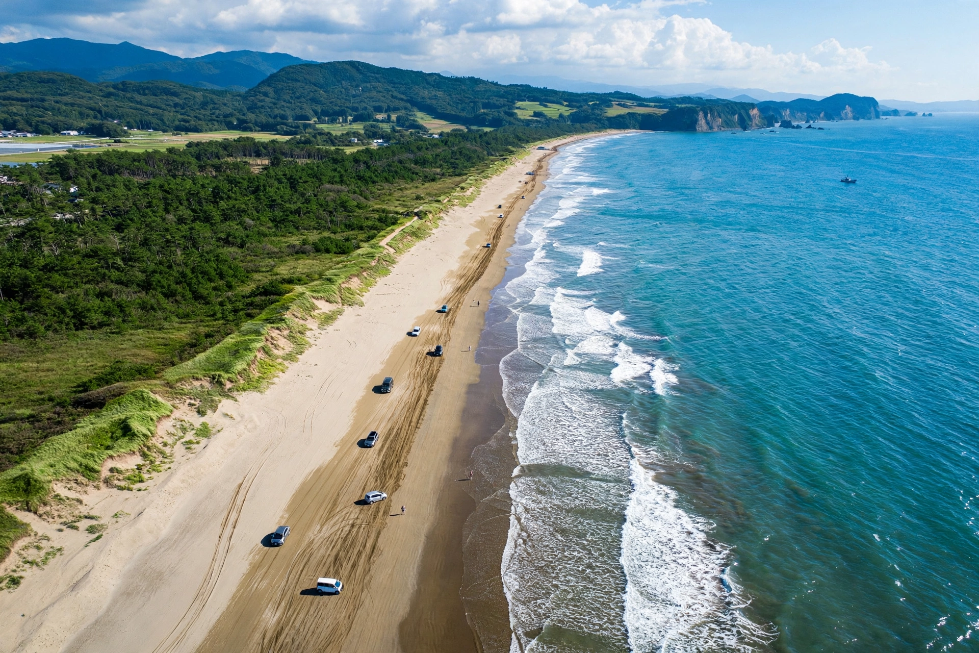 Cars driving along Chirihama Nagisa Driveway, the sandy beach road on the Noto Peninsula in Ishikawa, Japan